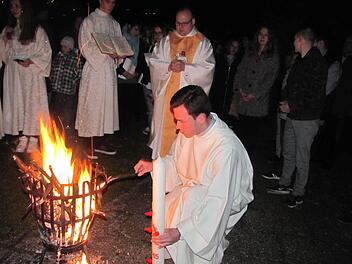 Kaplan Norbert Förster (hinten) und Pastoralreferent Sebastian König entzündeten am Osterfeuer vor der St.-Elisabeth-Kirche in Creidlitz die neue Osterkerze bei der Lichtfeier. Foto: Martin Koch