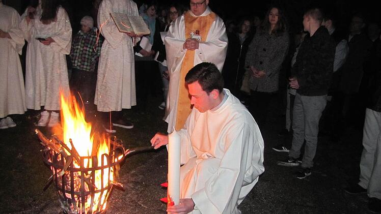 Kaplan Norbert Förster (hinten) und Pastoralreferent Sebastian König entzündeten am Osterfeuer vor der St.-Elisabeth-Kirche in Creidlitz die neue Osterkerze bei der Lichtfeier. Foto: Martin Koch