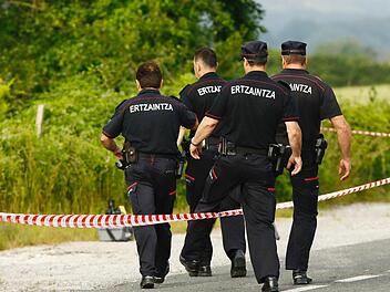 Polizisten steigen am Fundort einer Frauenleiche, nahe der Autobahn bei Asparrena, über eine Absperrung.   Jesus Andrade/El Correo/dpa