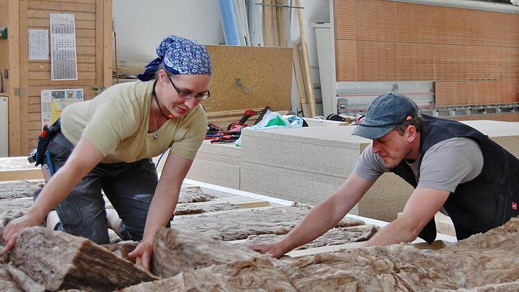 Zimmerin Tina Rössler mit ihrem Kollegen Claus Wehner beim Einlegen von Dämmmaterial in eine Fertighaus-Wand.
