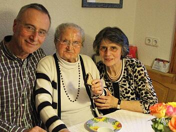 Auch an ihrem 100. Geburtstag fischt sich Anna Fößel ein knuspriges Gebäckstück vom Kuchenteller und beißt herzhaft ab. Mit auf dem Bild ihre beiden Kinder, Sohn Gerfried und Tochter Hildegund. Foto: Friedwald Schedel