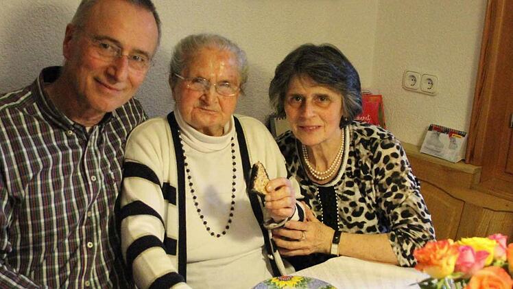 Auch an ihrem 100. Geburtstag fischt sich Anna Fößel ein knuspriges Gebäckstück vom Kuchenteller und beißt herzhaft ab. Mit auf dem Bild ihre beiden Kinder, Sohn Gerfried und Tochter Hildegund. Foto: Friedwald Schedel