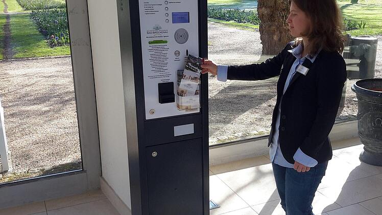 Gästebetreuerin Simone Nickolai bestückt den Tageskarten-Automaten mit Informationsmaterial. Das Gerät in der Wandelhalle des Staatsbades ist momentan Gesprächsthema in Bad Brückenau. Die Meinungen über die Neuerung gehen auseinander. Foto: Rolf Pralle