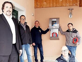 Bankchef Christian Senff, Ortssprecher Andreas Leibold, die Feuerwehr-Kommandant Winfried Walz und Christian Müller (von links) sowie vorne sitzend Dritter Bürgermeister Thomas Limpert mit einem der neuen Defibrillatoren