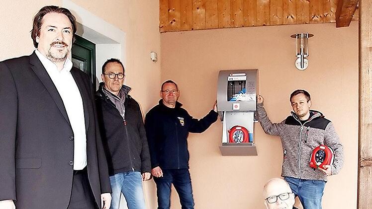 Bankchef Christian Senff, Ortssprecher Andreas Leibold, die Feuerwehr-Kommandant Winfried Walz und Christian Müller (von links) sowie vorne sitzend Dritter Bürgermeister Thomas Limpert mit einem der neuen Defibrillatoren