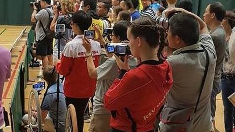 Sportler, Zuschauer und Medienleute stehen dicht gedrängt und halten die Kür digital fest. privat