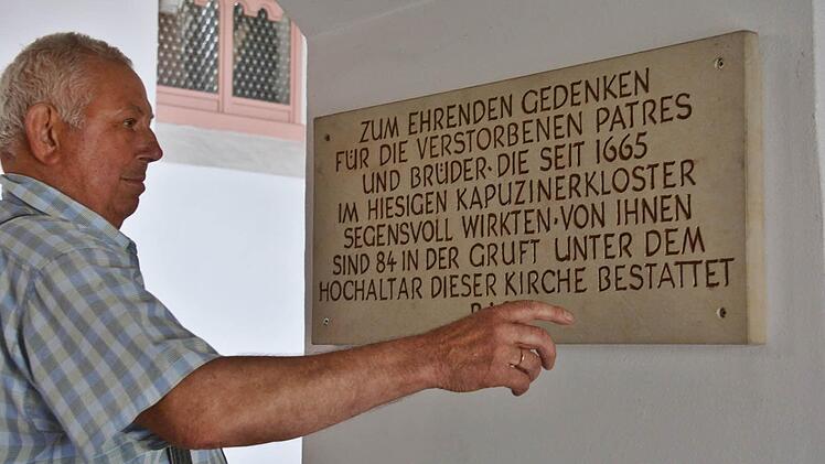 Mesner Winfried Schunk zeigt auf die Tafel, auf der vermerkt ist, dass unter dem Hochaltar 84 Patres begraben liegen. Foto: Hanns Friedrich