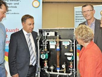 Innungsobermeister Jürgen Pillipp (l.) und Wolfgang Mevenkamp, Geschäftsführer der Innung (r.), erklären Landrat Tritthart, Erlangens Bürgermeisterin Lender-Cassens und dem Sprecher der Initiative Energiewende ER(H)langen, Stefan Jessenberger, die neuen Heizungspumpen.