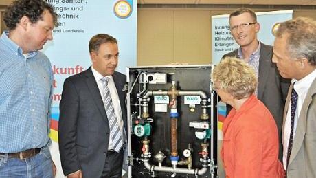 Innungsobermeister Jürgen Pillipp (l.) und Wolfgang Mevenkamp, Geschäftsführer der Innung (r.), erklären Landrat Tritthart, Erlangens Bürgermeisterin Lender-Cassens und dem Sprecher der Initiative Energiewende ER(H)langen, Stefan Jessenberger, die neuen Heizungspumpen.