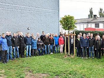 Gruppenbild mit Baum: Vertreter der Feuerwehren aus Ahorn und Sachsenbrunn haben den vor einem Jahr gepflanzten Ahorn, ein Geschenk, in ihre Mitte genommen.  Foto: Karl-Wolfgang Flei&szlig;ig