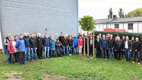 Gruppenbild mit Baum: Vertreter der Feuerwehren aus Ahorn und Sachsenbrunn haben den vor einem Jahr gepflanzten Ahorn, ein Geschenk, in ihre Mitte genommen.  Foto: Karl-Wolfgang Flei&szlig;ig