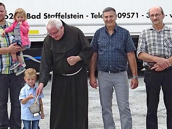In Gegenwart der Familie Schad vom Transportunternehmen CS-Trans aus Grundfeld (l.), von Jürgen Hofmann (r.) und des Fahrers Siegfried Keller (2. v. r.) segnete Pater Heribert Arens (3. v. r.) das Fahrzeug und den Fahrer für die lange Reise nach Rumänien.  Foto: Alfred Thieret