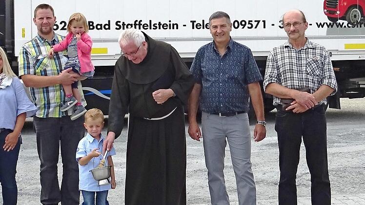 In Gegenwart der Familie Schad vom Transportunternehmen CS-Trans aus Grundfeld (l.), von Jürgen Hofmann (r.) und des Fahrers Siegfried Keller (2. v. r.) segnete Pater Heribert Arens (3. v. r.) das Fahrzeug und den Fahrer für die lange Reise nach Rumänien.  Foto: Alfred Thieret