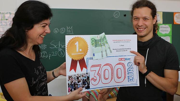 Christine Martin übergibt Lukas Gosoge, Lehrer an der Martinschule Bamberg, das Preisgeld für die 3a und die 3b. Foto: Barbara Herbst