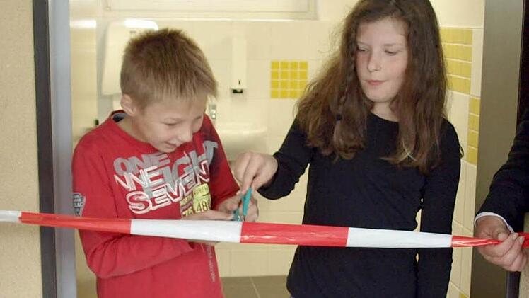 Spaß muss sein - Jannik Kotschenreuther und Kira Engelhardt durchschneiden das Band zur "Eröffnung der neuen Schultoiletten". Foto: Susanne Deuerling