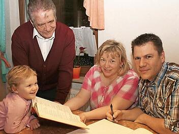 Auf zwei Seiten hat Michael Malzer (rechts) das Evangelium vom ersten Fastensonntag aufgeschrieben. Seine Frau Marion hält die Vorlage, ein gedrucktes Evangelienbuch in Händen. Im Bild stehend Pater Gabriel Ramos (noch mit Aschenkreuz auf der Stirn) und die jüngste der Familie, Miriam Malzer Foto: Evi Seeger