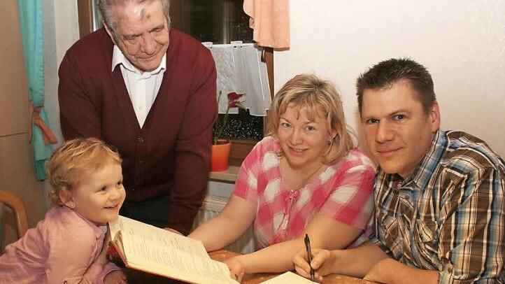 Auf zwei Seiten hat Michael Malzer (rechts) das Evangelium vom ersten Fastensonntag aufgeschrieben. Seine Frau Marion hält die Vorlage, ein gedrucktes Evangelienbuch in Händen. Im Bild stehend Pater Gabriel Ramos (noch mit Aschenkreuz auf der Stirn) und die jüngste der Familie, Miriam Malzer Foto: Evi Seeger