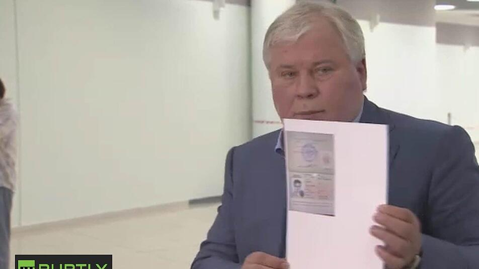 Anatoly Kucherena, Anwalt von Edward Snowden, zeigt die Papiere, die es dem Geheimdienstexperten erlauben, in Russland zu bleiben. Foto: RT PUPTLY/dpa