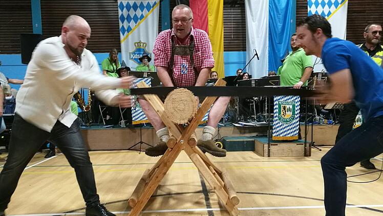 Ralf Leipold (Mitte auf dem Bock) überwacht den Sägewettbewerb. Im Hintergrund der Musikverein Wallenfels.privat