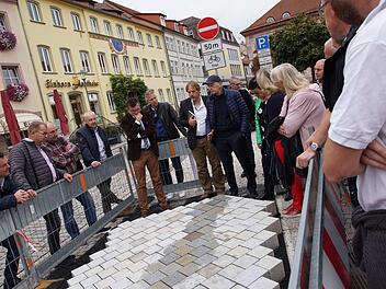 Bürgermeister Armin Warmuth, Stadtbaumeister Detlef Mohr und Architekt Hartmut Holl beugen sich mit den Stadträten über die Musterpflasterfläche am Marktplatz. Foto: Arkadius Guzy