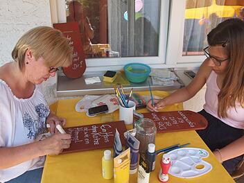 Zwei Frauen bemalen einen Ziegel mit Bildern und einem Spruch, wobei sich Rosi Vollert (links) als Katzenfreundin outet. Fotos: Alfred Thieret