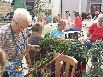 Christine Seitz (l.) beim Binden der Kränze für den Osterbrunnen