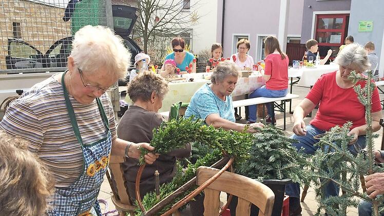Christine Seitz (l.) beim Binden der Kränze für den Osterbrunnen