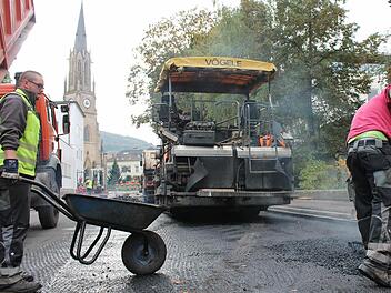 Vorbereitende Arbeiten: Johann Bauer (links) von der Asphaltkolonne verteilt 170 Grad heißen Asphalt mit einer Schubkarre auf die Straße. Fotos: Benedikt Borst