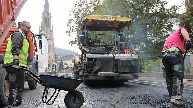 Vorbereitende Arbeiten: Johann Bauer (links) von der Asphaltkolonne verteilt 170 Grad heißen Asphalt mit einer Schubkarre auf die Straße. Fotos: Benedikt Borst