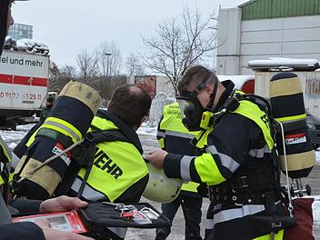 Mit schwerem Atemschutz gehen Feuerwehrleute abwechselnd vor, um die brennende Gasflasche zu kühlen. Fotos: Rainer Lutz