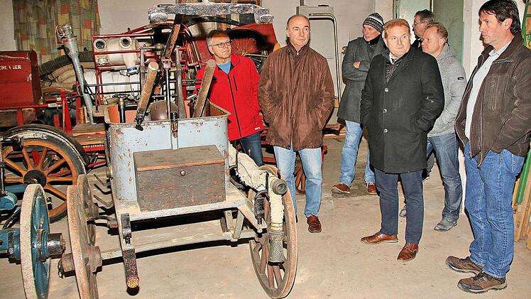 Alte, museumsreife Feuerwehrgeräte lagern in einem Schuppen neben dem Haus Hauptstraße 69 in Poppenlauer. Nach einem Ortstermin war sich der Marktgemeinderat einig darüber, dass das Gebäude samt Schuppen veräußert werden sollte. Unser Bild zeigt Marktgemeinderäte und Bürgermeister Klement in dem Gebäudeteil mit den Feuerwehrgerätschaften. Auf einer Spritze steht "Gemeinde Poppenlauer 1933".  Foto: Dieter Britz