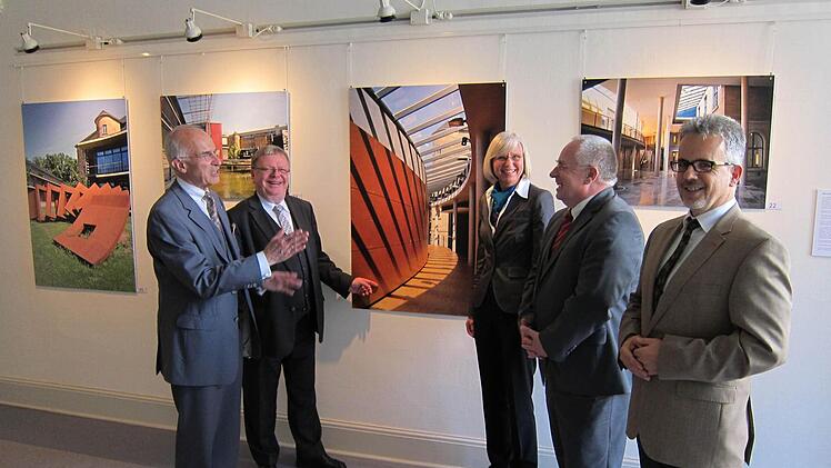 Vor Fotos des Justizgebäudes in Würzburg stehen bei der Ausstellungseröffnung in Bamberg (von links) Ministerialdirektor Walter Schön, OLG-Präsident Clemens Lückemann, Ministerialrätin und Architektin Gabriele Engel, Generalstaatsanwalt Thomas Janovsky und der Fotografen und Vizepräsident des Landgerichts Hof, Matthias Burghardt.