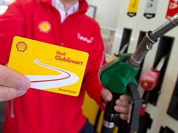 Ein Shell-Mitarbeiter zeigt an einer Tankstelle die Shell-Rabattkarte ClubSmart. Die Karte soll das Tanken günstiger machen, wirbt Shell. Foto: Christian Charisius, dpa