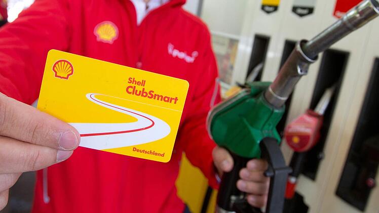 Ein Shell-Mitarbeiter zeigt an einer Tankstelle die Shell-Rabattkarte ClubSmart. Die Karte soll das Tanken günstiger machen, wirbt Shell. Foto: Christian Charisius, dpa