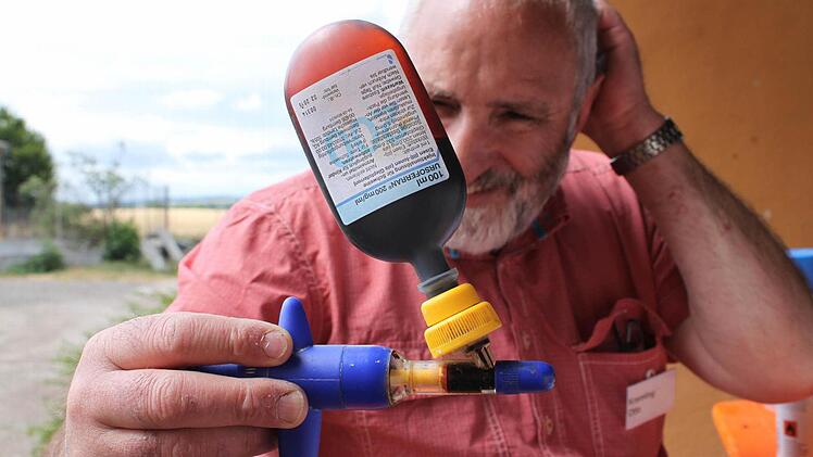 Prüfer Otto Kremling hält eine Spritze in der Hand, mit der Landwirte ihren Ferkeln in den ersten Lebenstagen Eisen spritzen.