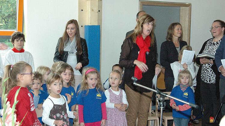 "Kapitän des Kindergartens", Leiterin Carola Caupert- Müller (mit rotem Schal) und die Kindergartenkinder sangen kräftig bei der Einweihung ihres neuen Heimes mit. Foto: gsch