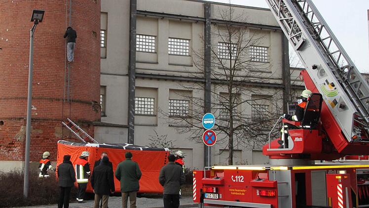 Der Asylbewerber hat aufgegeben: Er klettert vom Spinnerei-Schlot wieder nach unten, wo er sich in 30 Metern Höhe eine Stunde lang festgeklammert und droht hat, in die Tiefe zu springen. Fotos: Stephan Tiroch