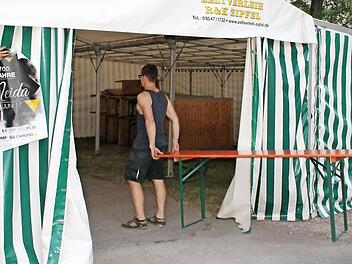 Marcel Renner(l.) bringt ein Plakat am Zelt an, Simon Taubmann (M.) und Tim Karl statten das Innere mit Biertischgarnituren aus.