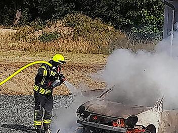 Die Feuerwehrleute beim "Einsch&auml;umen" des brennenden Autos.