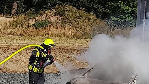 Die Feuerwehrleute beim "Einsch&auml;umen" des brennenden Autos.