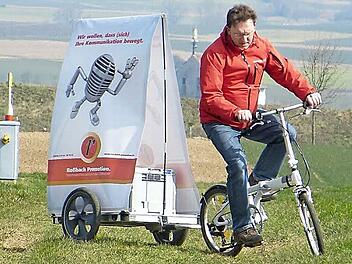 Entwickler Volker Roßbach und sein patentierter Fahrradanhänger: Jetzt noch bei Sturm in der Rhön getestet - ab dem Sommer soll der Anhänger in den Fußgängerzonen deutscher Metropolen Unternehmen als flexibler Werbeträger dienen.  Foto: Roland Brandt