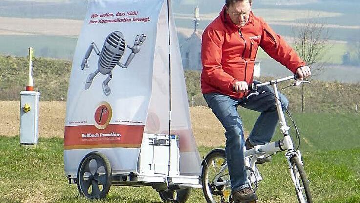 Entwickler Volker Roßbach und sein patentierter Fahrradanhänger: Jetzt noch bei Sturm in der Rhön getestet - ab dem Sommer soll der Anhänger in den Fußgängerzonen deutscher Metropolen Unternehmen als flexibler Werbeträger dienen.  Foto: Roland Brandt