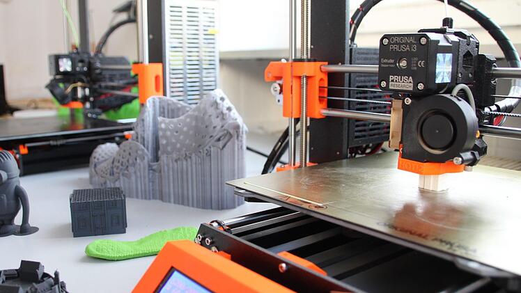 Der 3D-Drucker stellt die weiße Miniatur (rechts unter dem Druckkopf) etwa 40 Minuten lang her.