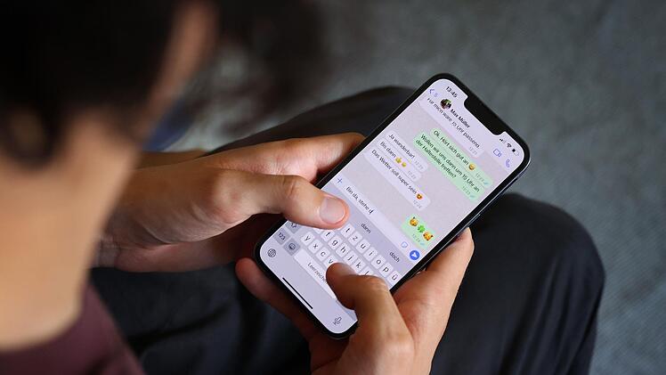 Ein junger Mann tippt eine WhatsApp Nachricht.  Karl-Josef Hildenbrand/dpa