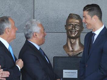 Sehen sich zum verwechseln &auml;hnlich: Cristiano Ronaldo (rechts) und seine B&uuml;ste (zweiter von rechts) im umbenannten "Cristiano Ronaldo Airport" auf Madeira. Foto: Armando Franca/AP/dpa