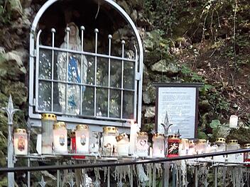 Neben der Marienfigur steht eine Tafel, mit der Bitte, vom übermäßigen Abbrennen von Kerzen in Plastikhüllen abzusehen. Diese wird ignoriert.Marion Ender