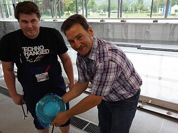 Sebastian Danz und Edgar Beck zeigen einen der neuen Scheinwerfer für das Hallenbecken. Foto: Arkadius Guzy