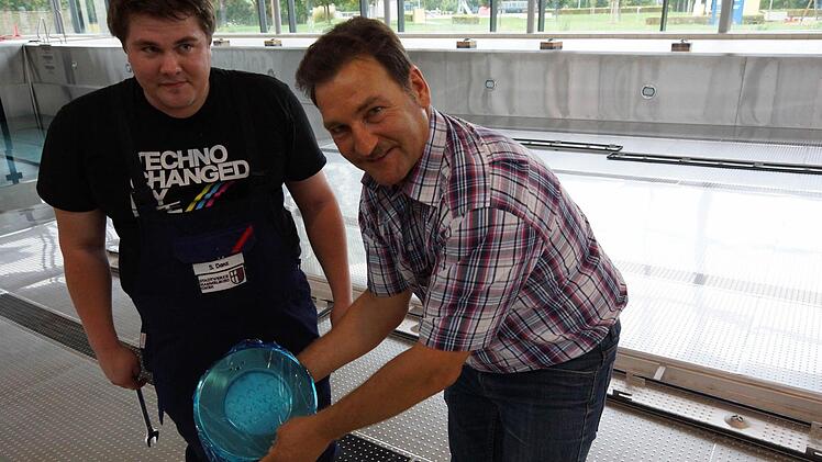 Sebastian Danz und Edgar Beck zeigen einen der neuen Scheinwerfer für das Hallenbecken. Foto: Arkadius Guzy