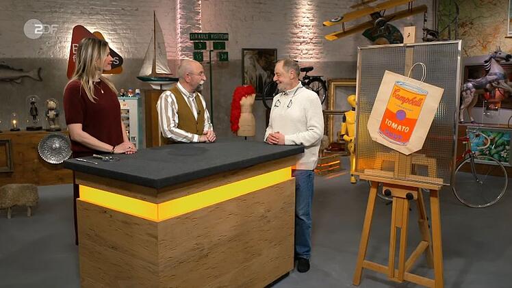 Verk&auml;ufer Franz-Josef (rechts) bringt einen Farbsiebdruck auf einer Papiert&uuml;te mit. Der Druck stammt aus dem Jahr 1966 und ist von Andy Warhol. Franz-Joseph ist mit dem Ergebnis zufrieden: Er kann er das St&uuml;ck f&uuml;r 1.650 Euro an den Kunsth&auml;ndler Julian Schmitz-Avila verkaufen.