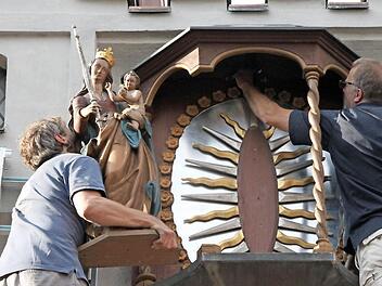 Stefan Lochner hebt die Muttergottes in das Kapellchen, während Norbert Düring die letzten Schrauben festdreht.Fotos: Heike Beudert